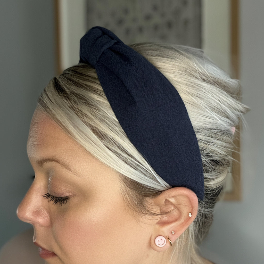 Person wearing a navy blue headband with a neutral background